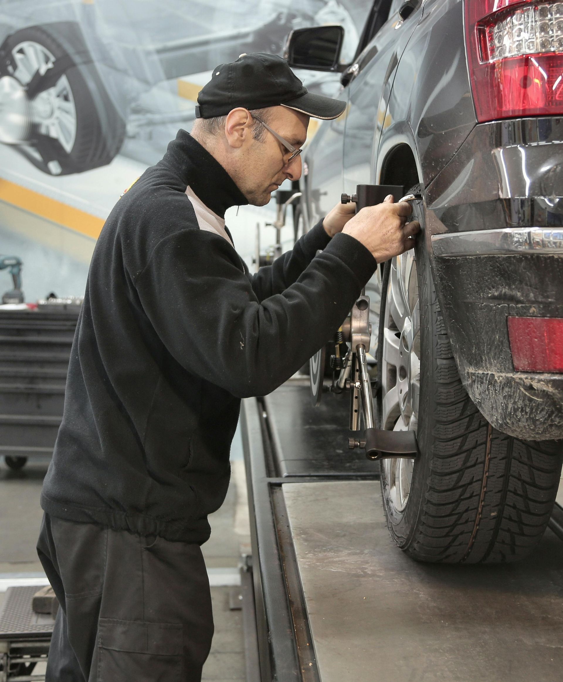 Mechanic inspecting a black SUV’s rear wheel in an auto repair shop
