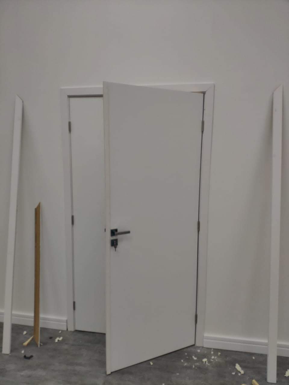 Uma porta branca está aberta em uma sala vazia.