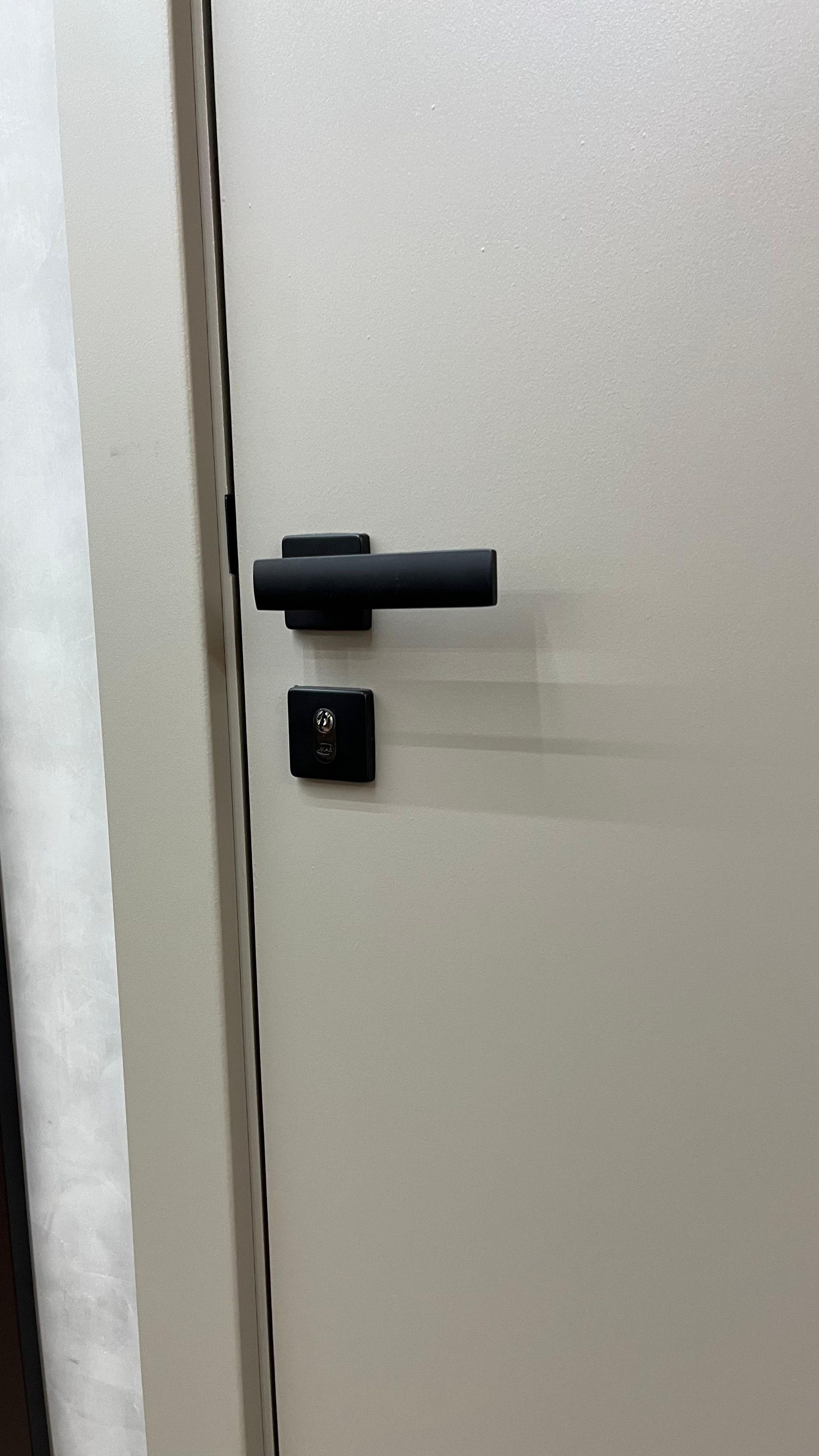 Uma porta branca com uma maçaneta preta.