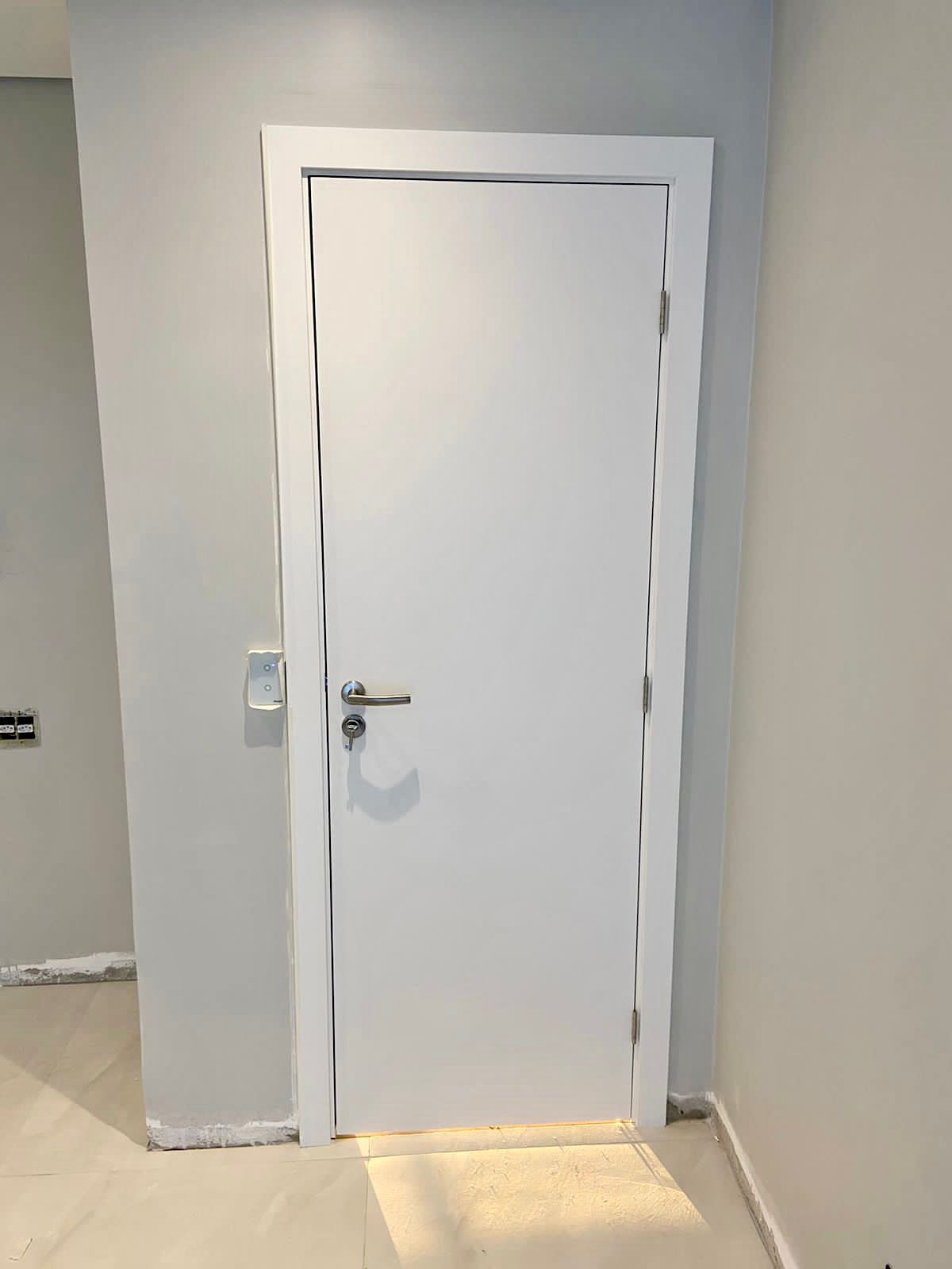 Uma porta branca está em um corredor ao lado de uma parede.