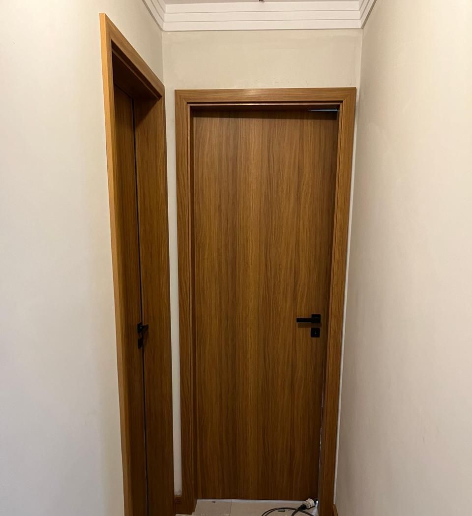 Um corredor com duas portas de madeira e uma parede branca.