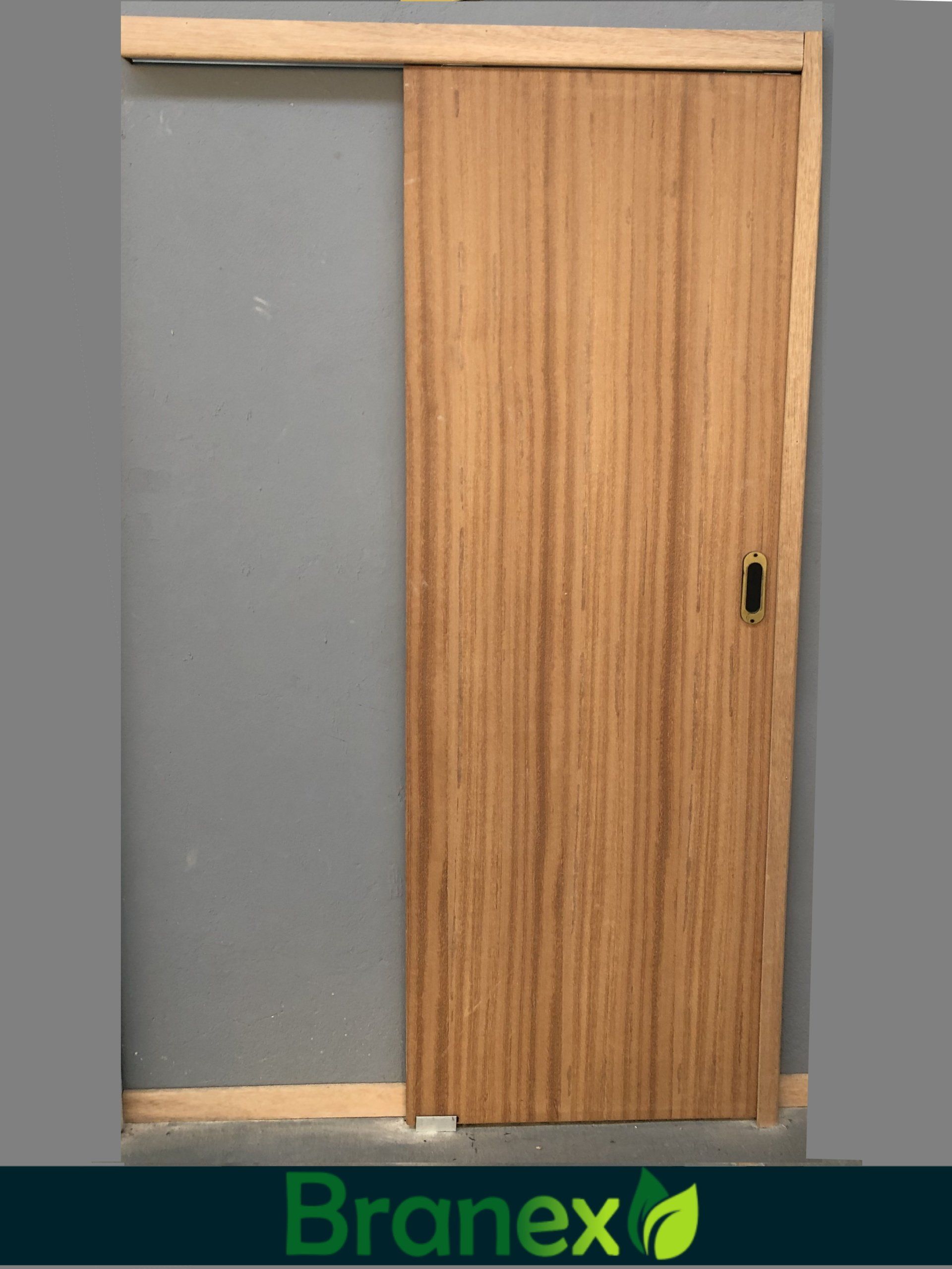 Uma porta de correr de madeira está pendurada em uma parede cinza.