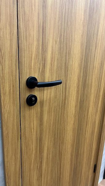 Um close de uma porta de madeira com uma maçaneta preta.