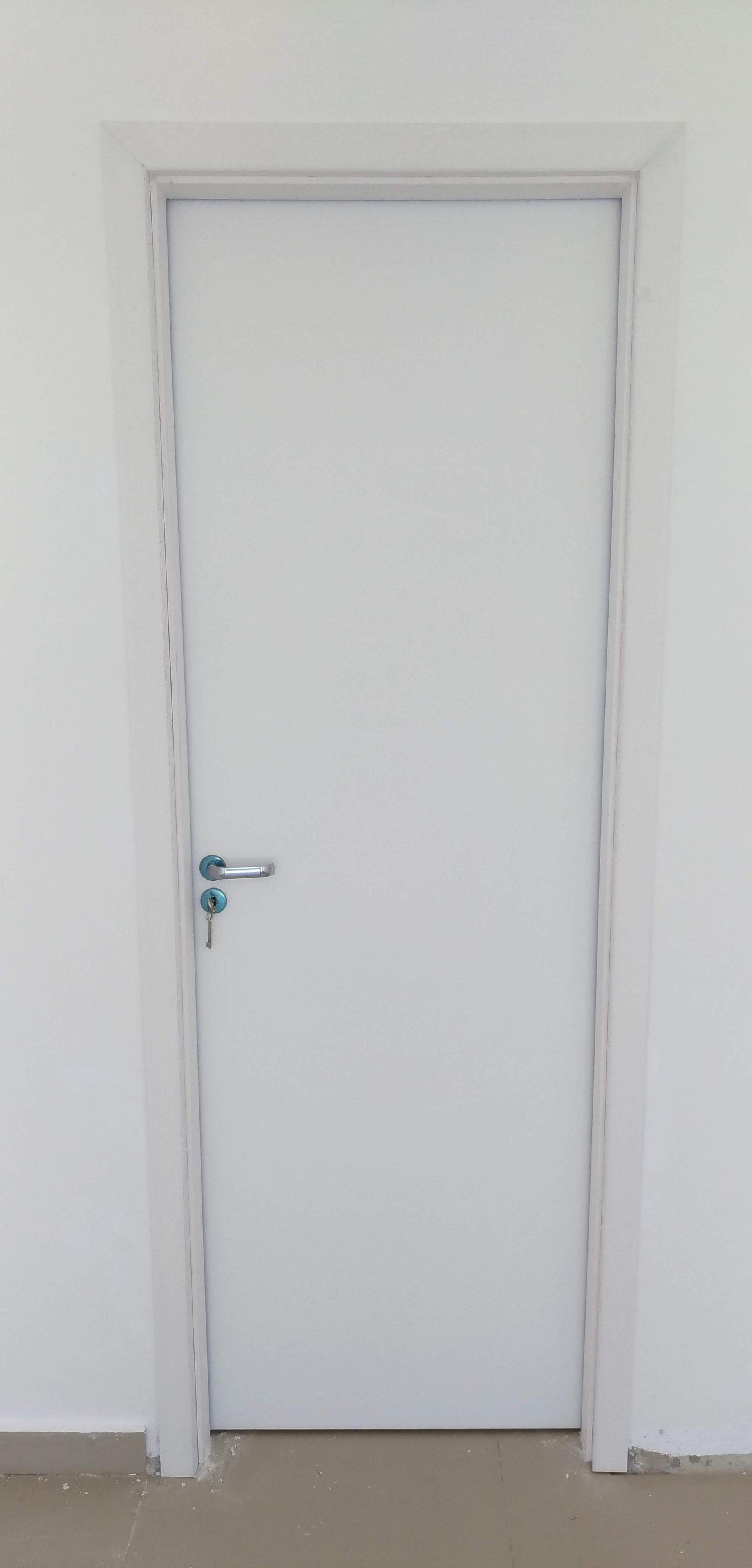 Uma porta branca está em uma sala com uma parede branca.