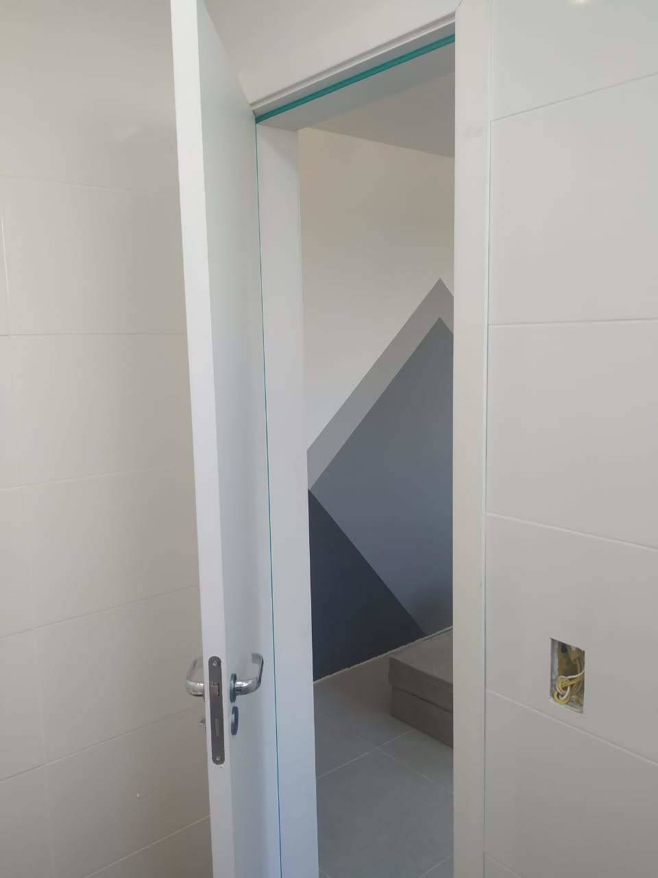 Uma porta branca está aberta para uma escada em uma sala.