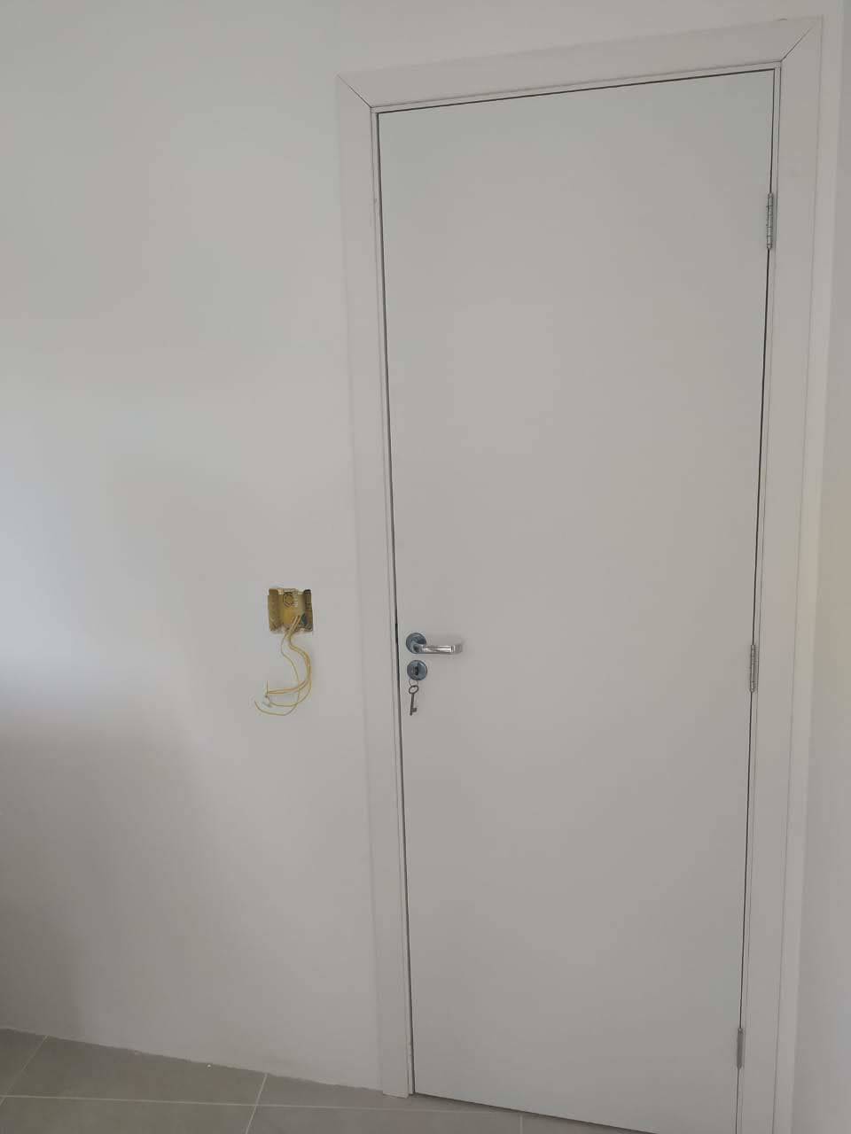 Uma porta branca com uma chave está em uma sala.