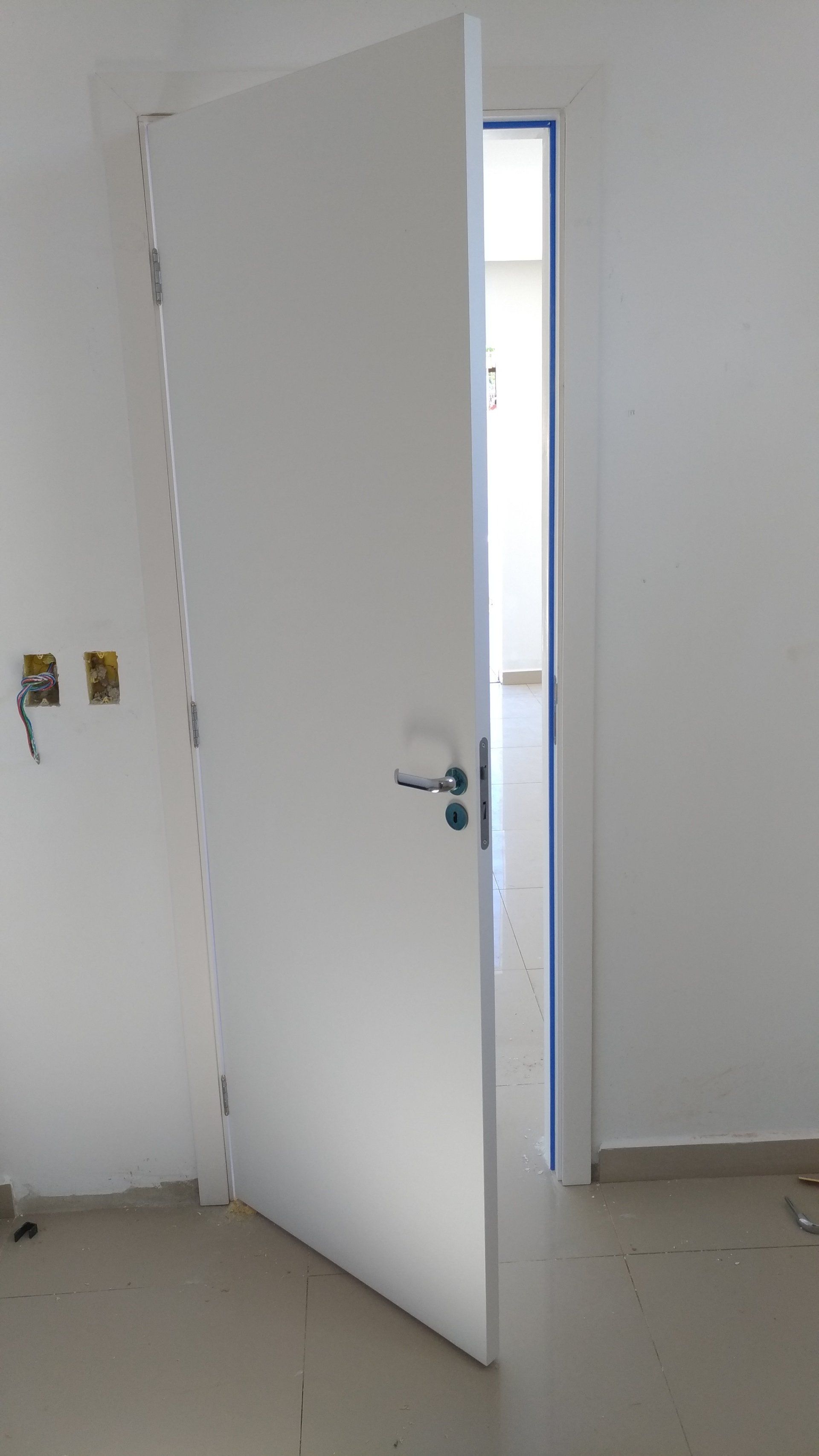 Uma porta branca está aberta em uma sala vazia.