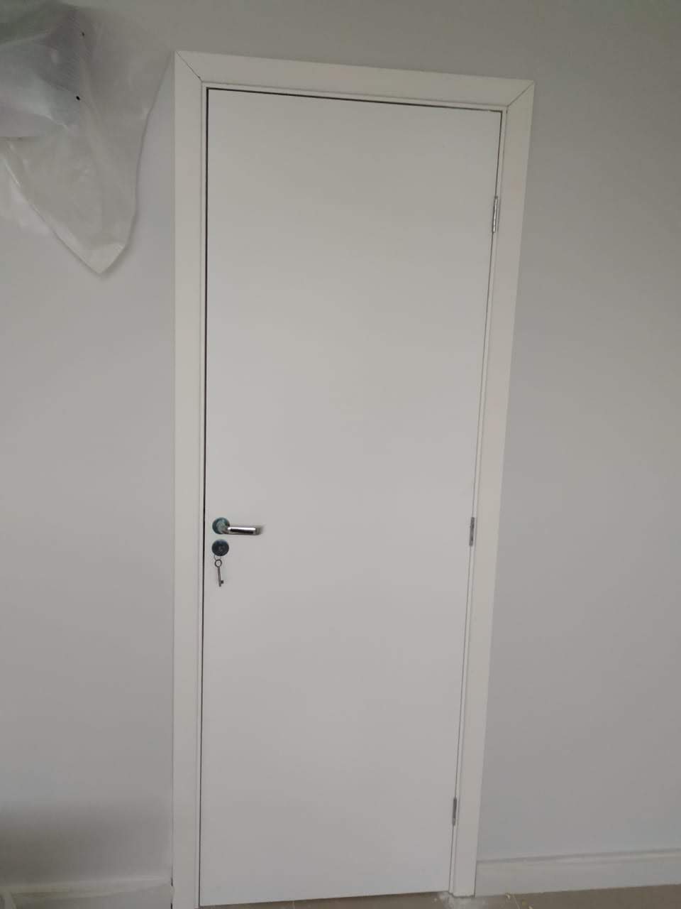 Uma porta branca com uma chave está em uma sala.