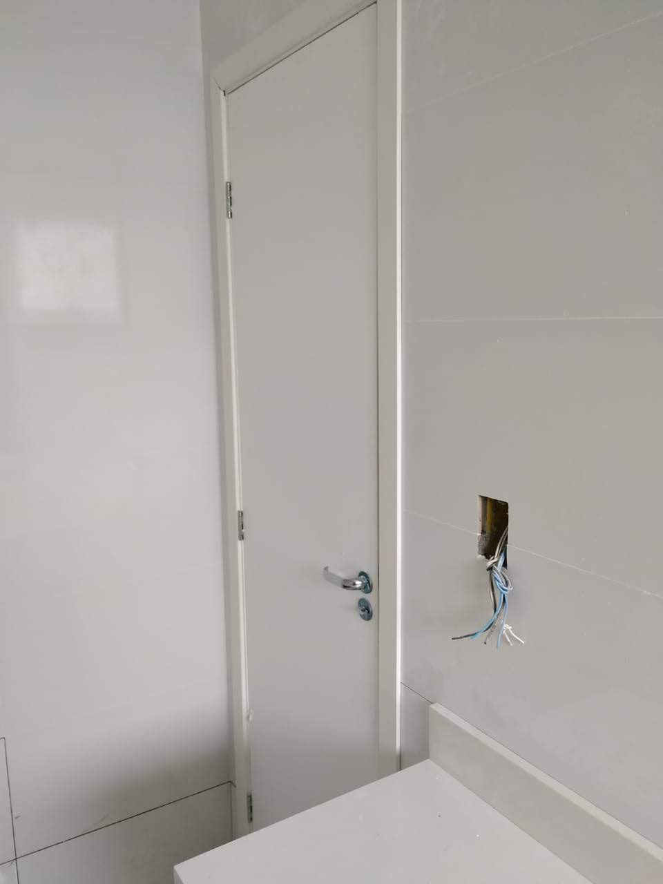 Um banheiro com uma porta branca e um buraco na parede