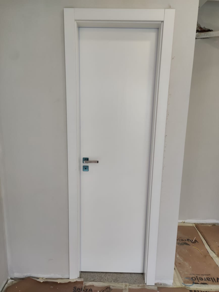 Uma porta branca está sendo instalada em uma sala.