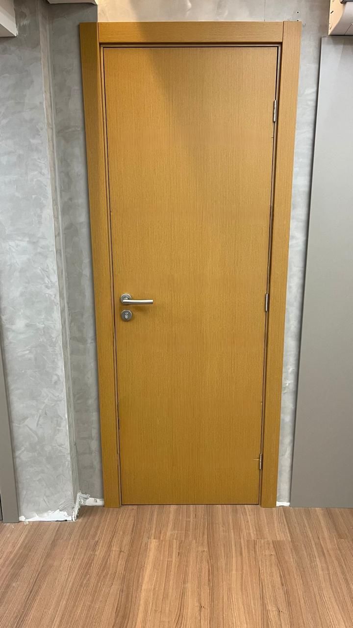 Uma porta de madeira está sobre um piso de madeira em uma sala.