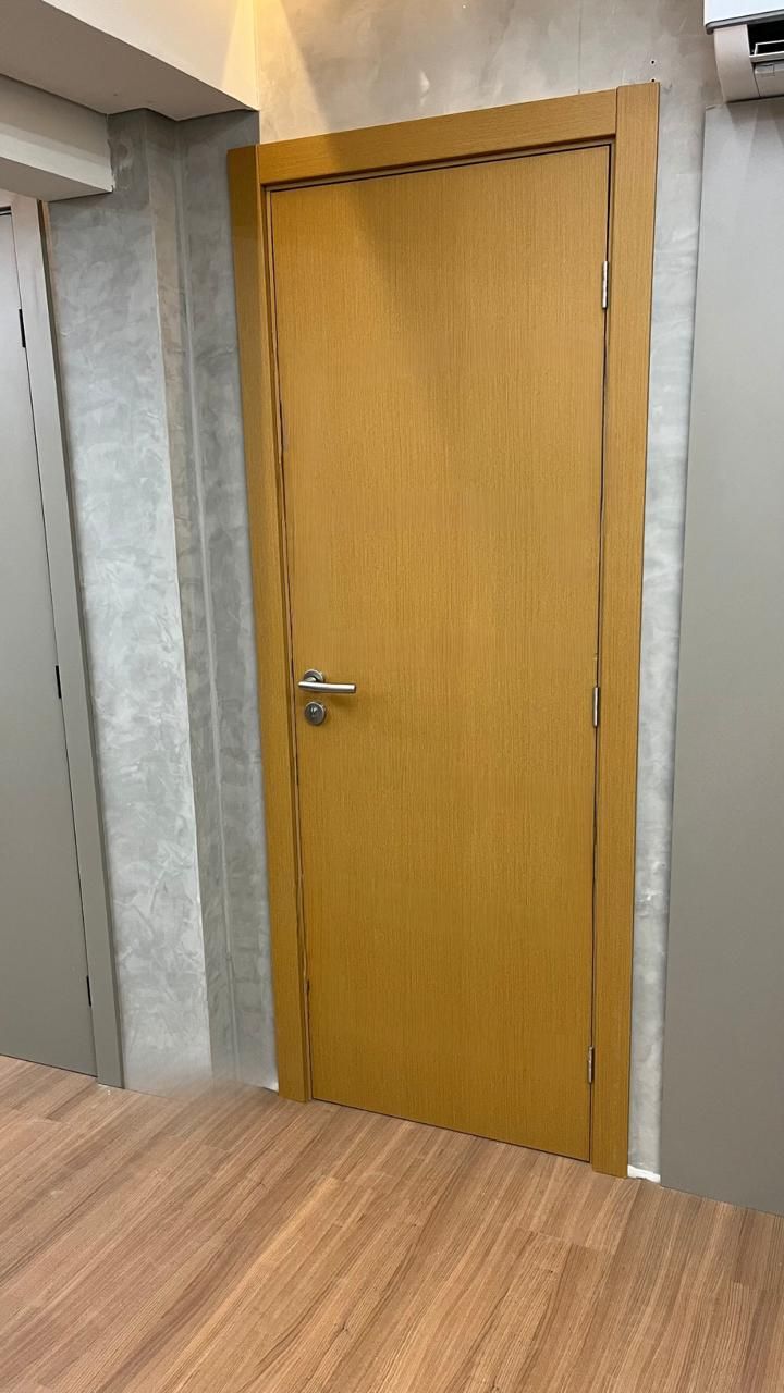 Uma porta de madeira está em uma sala com piso de madeira.