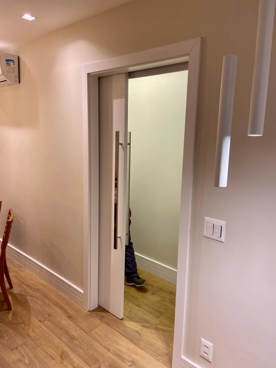 Uma pessoa está parada em uma sala com uma porta de vidro deslizante.