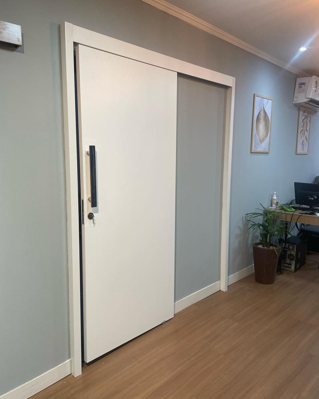 Uma porta de correr branca fica em um corredor ao lado de uma mesa.