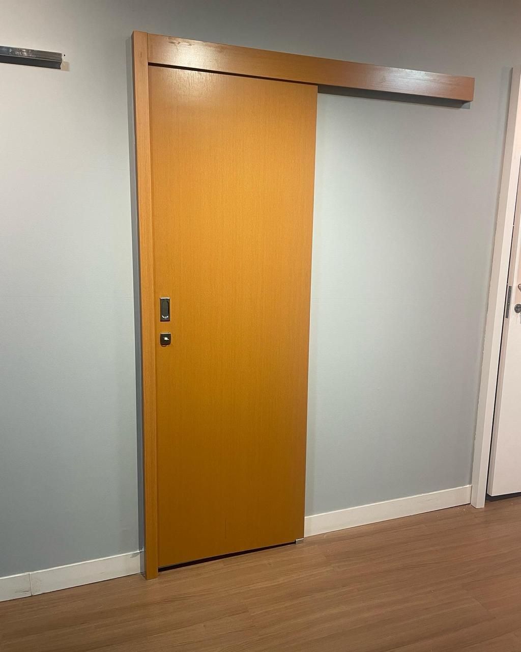 Uma porta de correr de madeira está pendurada na parede de uma sala.