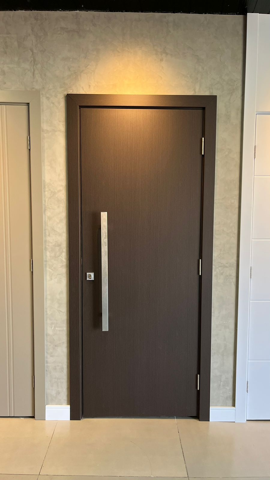 Uma porta de madeira com uma maçaneta de metal está pendurada na parede de uma sala.