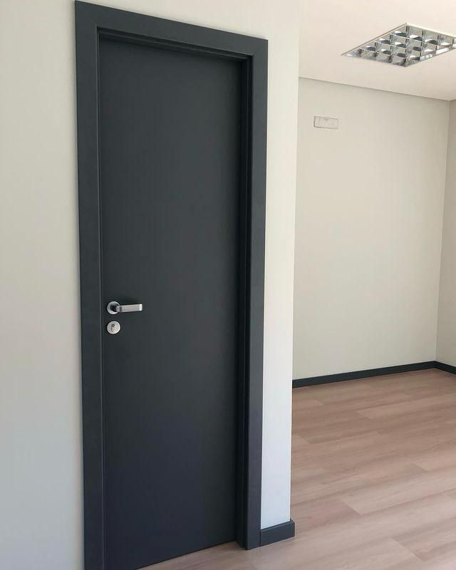 Há uma porta preta no meio de uma sala.