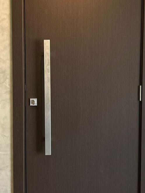 Um close de uma porta marrom com uma maçaneta de aço inoxidável.