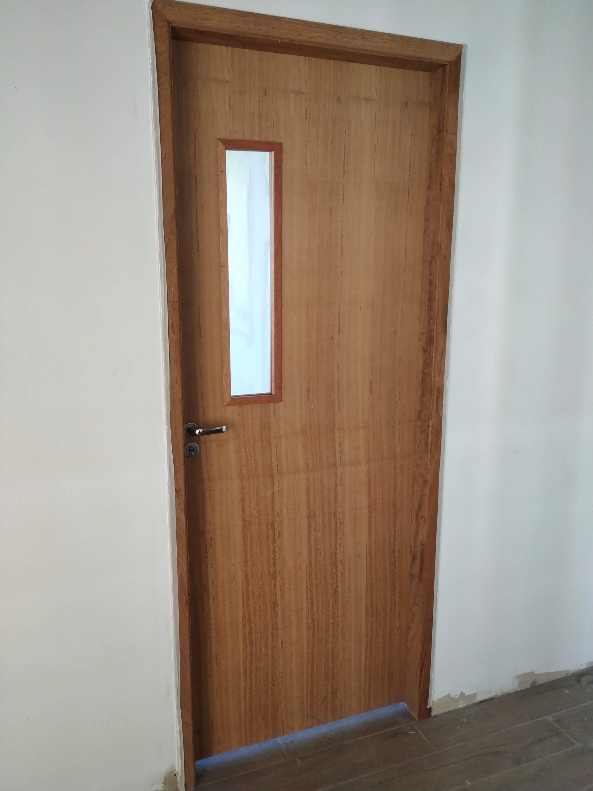 Uma porta de madeira com uma pequena janela em uma sala.