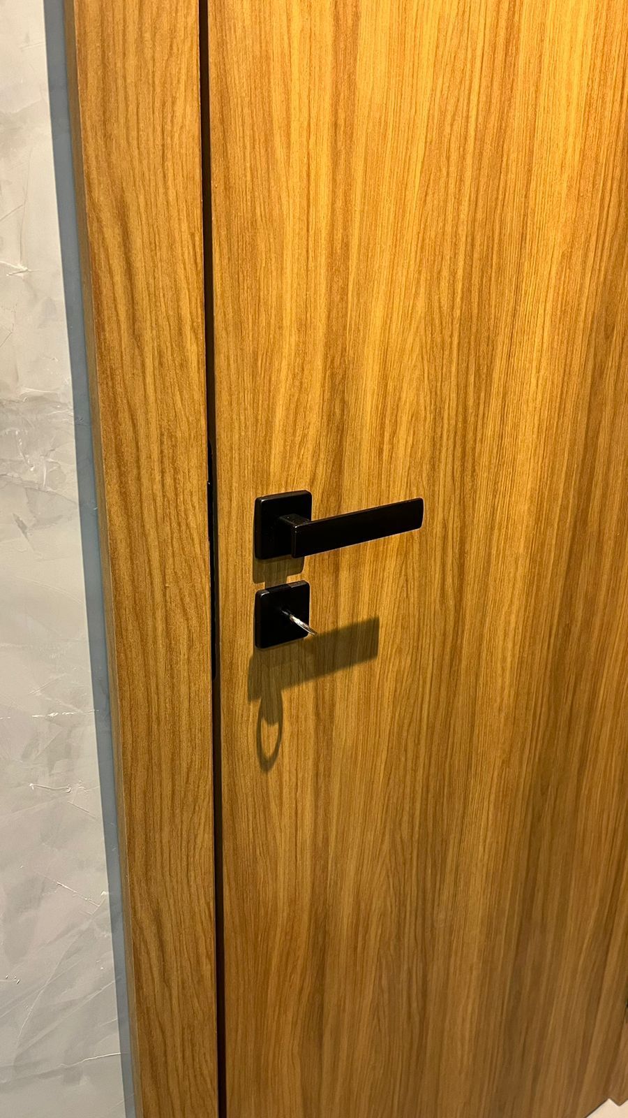 Um close de uma porta de madeira com uma maçaneta preta.