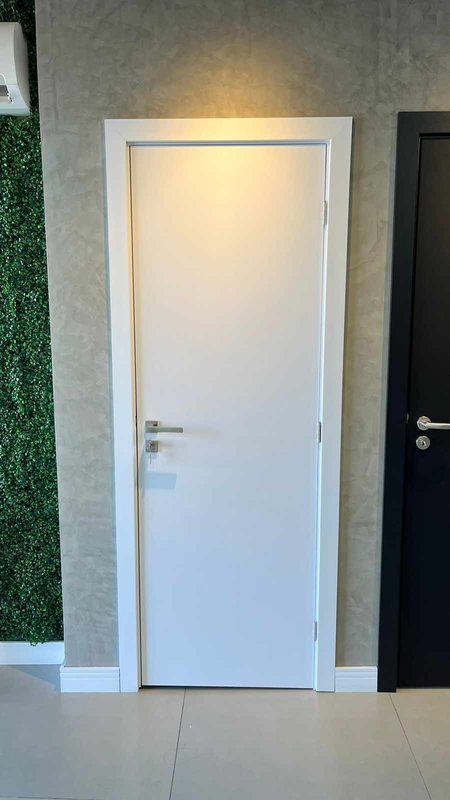 Uma porta branca está ao lado de uma porta preta em uma sala.