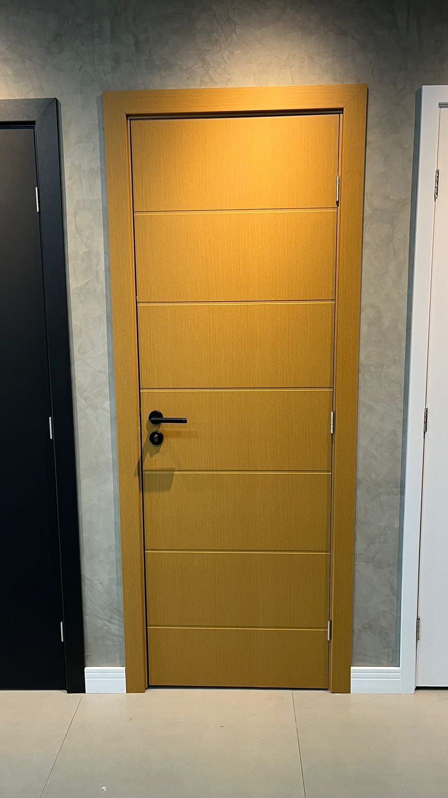 Uma porta de madeira está ao lado de uma porta preta e uma porta branca.