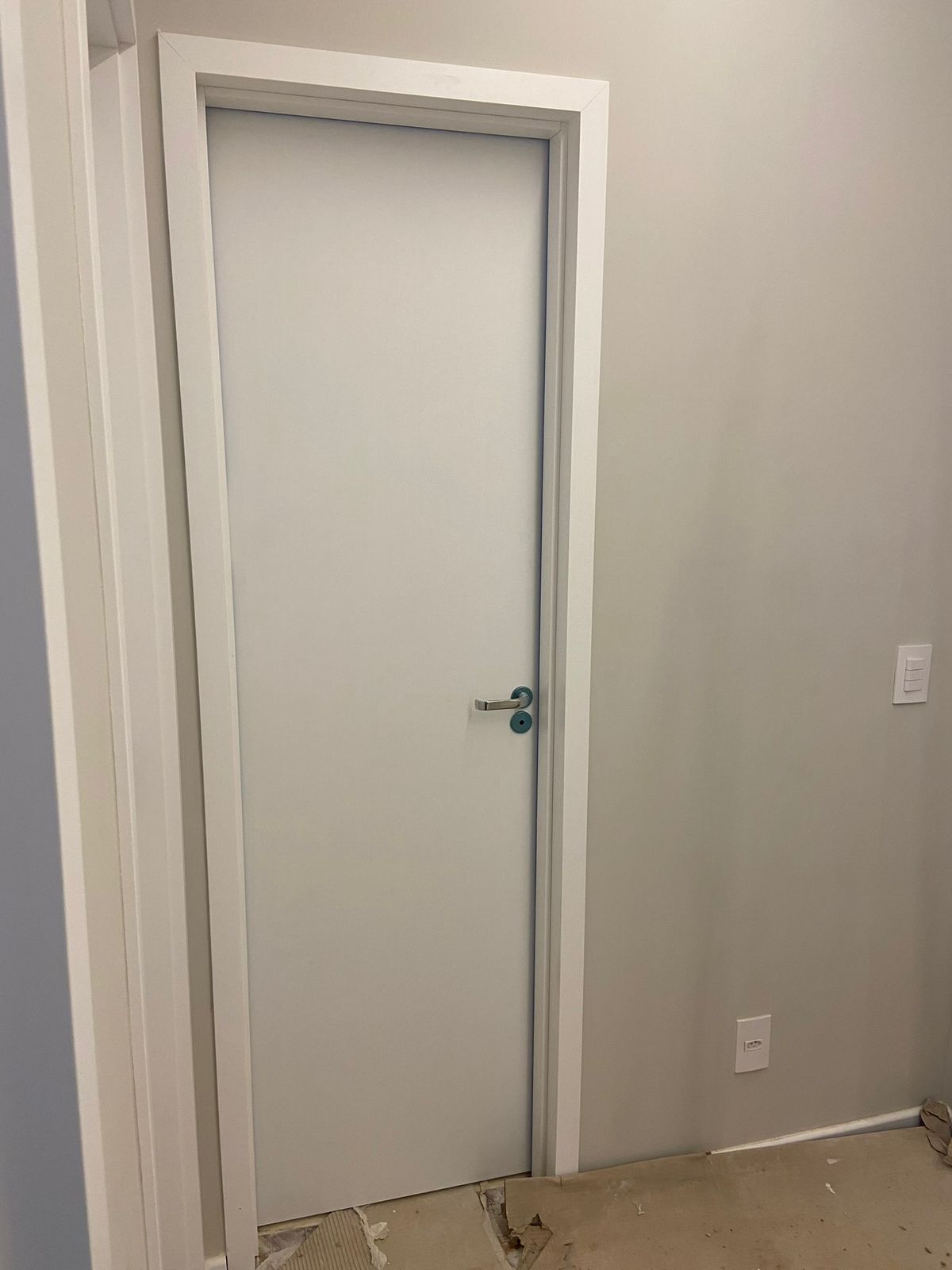 Uma porta branca com uma moldura branca está em uma sala.