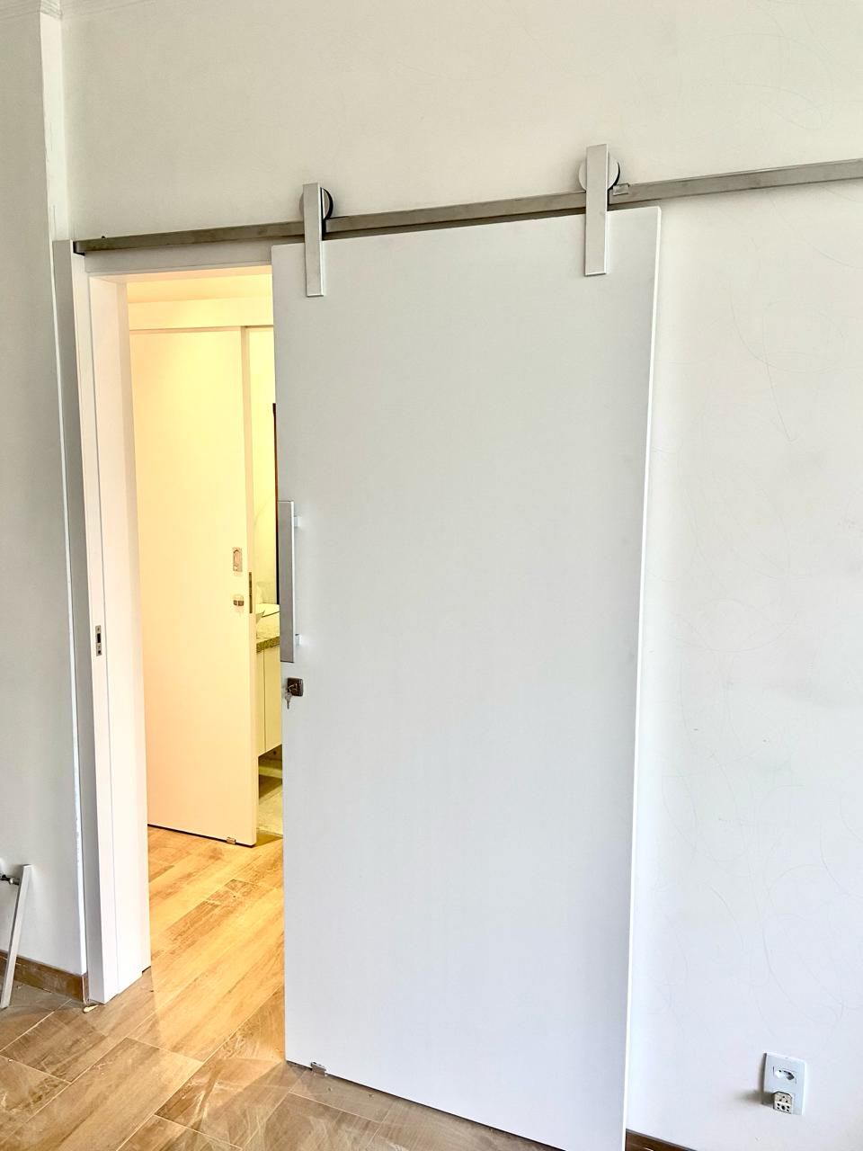 Uma porta de correr branca de celeiro está aberta em uma sala