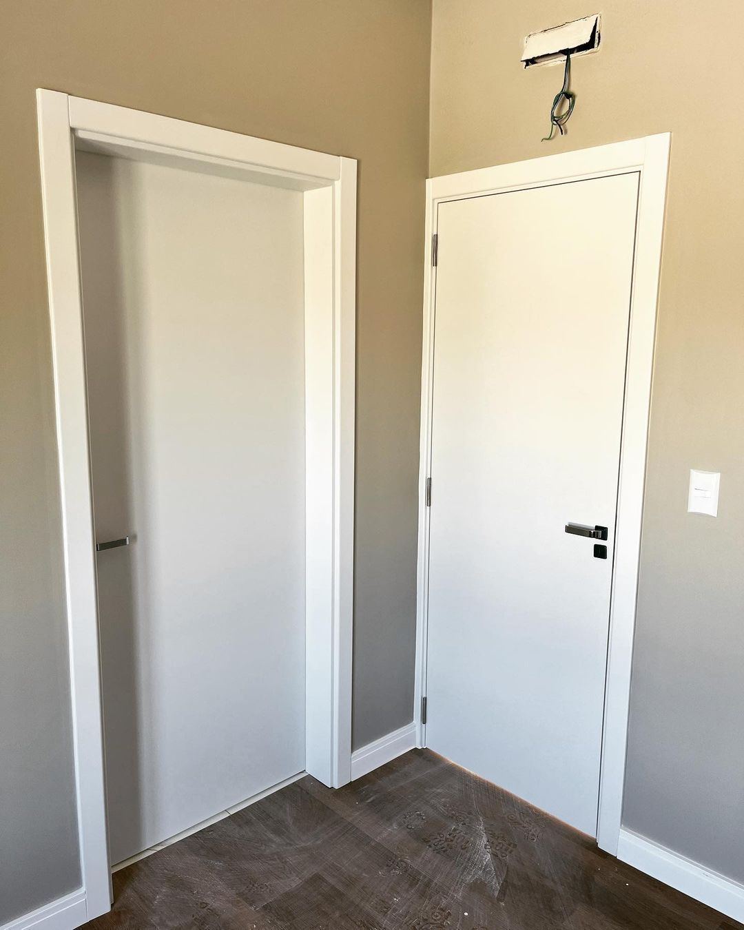 Um canto de uma sala com duas portas brancas e uma câmera na parede.