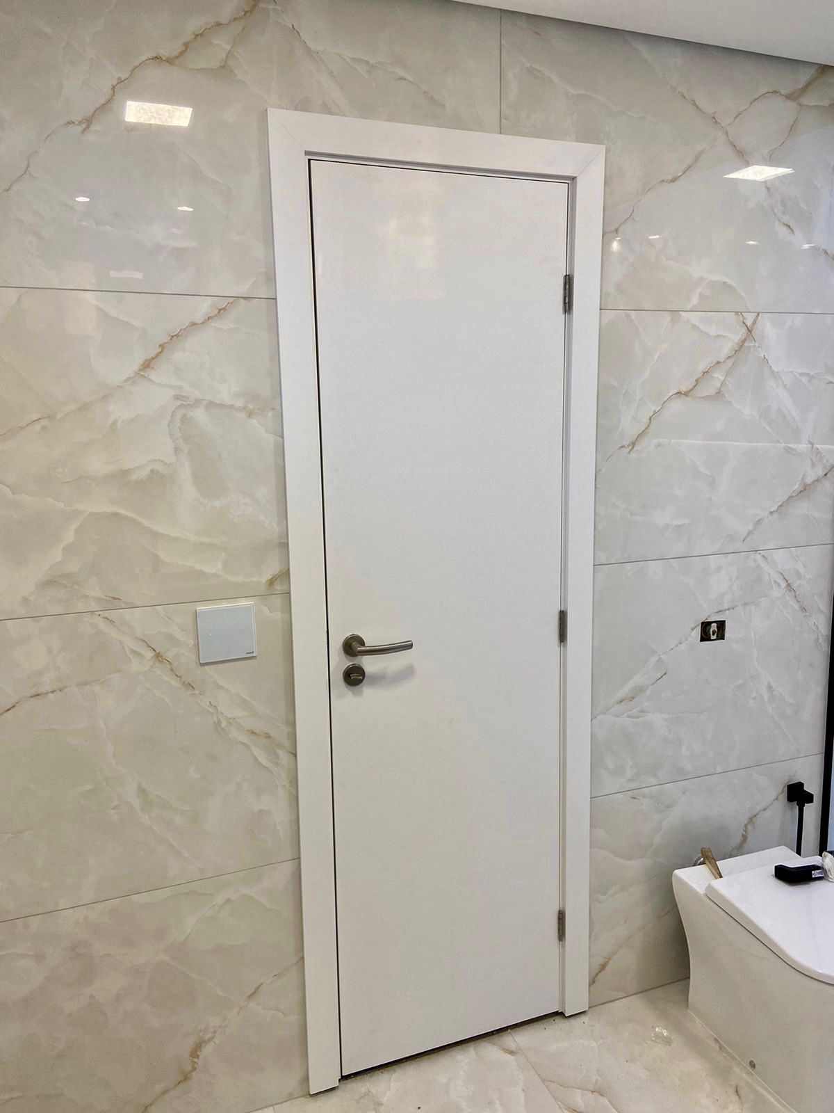 Uma porta branca está em um banheiro ao lado de um vaso sanitário.