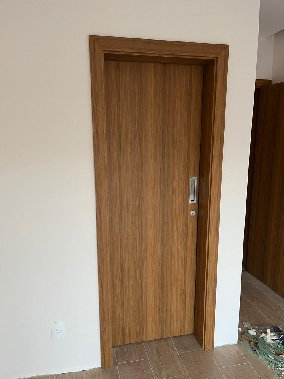 Uma porta de madeira está contra uma parede branca em uma sala.