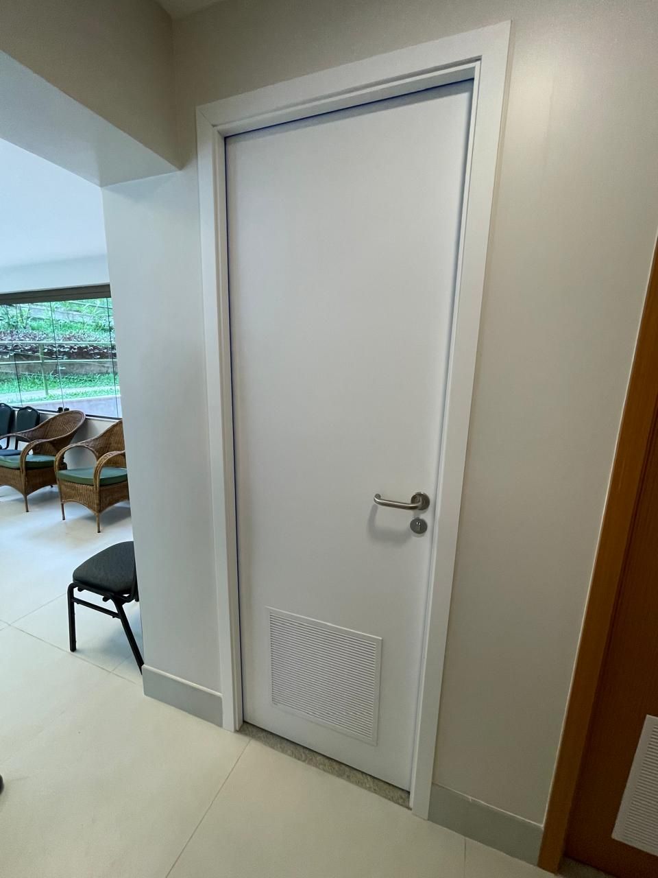 Uma porta branca está em um corredor que leva a uma sala de estar.