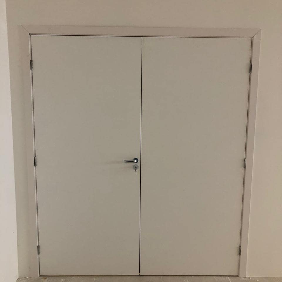 Um par de portas duplas brancas com uma chave em um quarto.