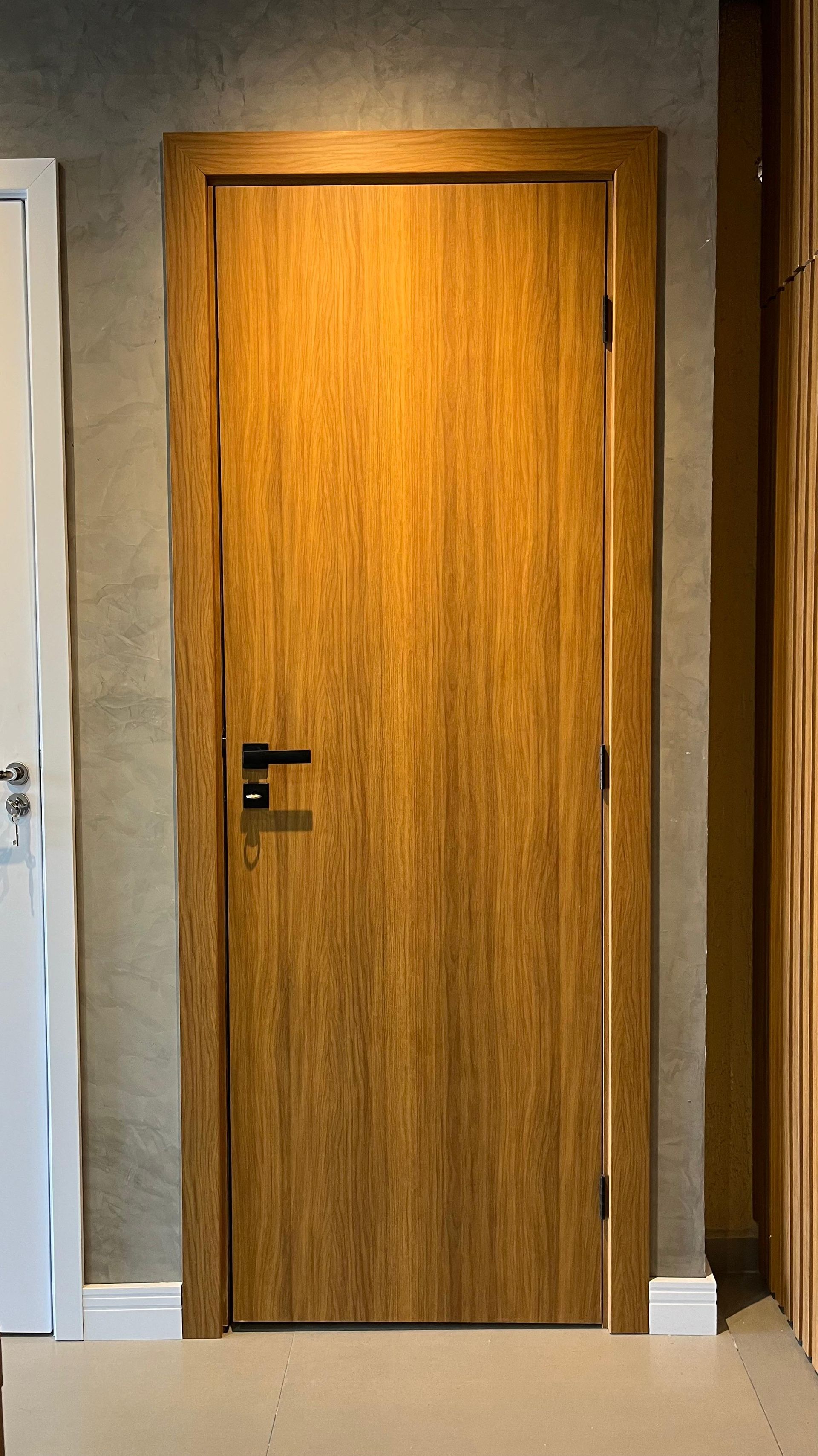 Uma porta de madeira está em um corredor ao lado de uma porta branca.