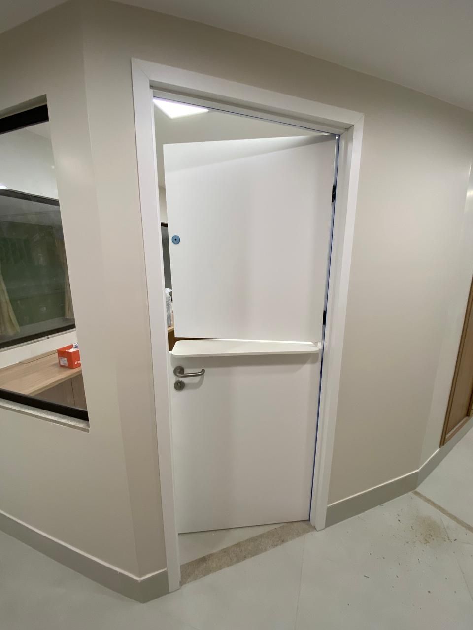 Uma porta branca está aberta em uma sala com uma janela.