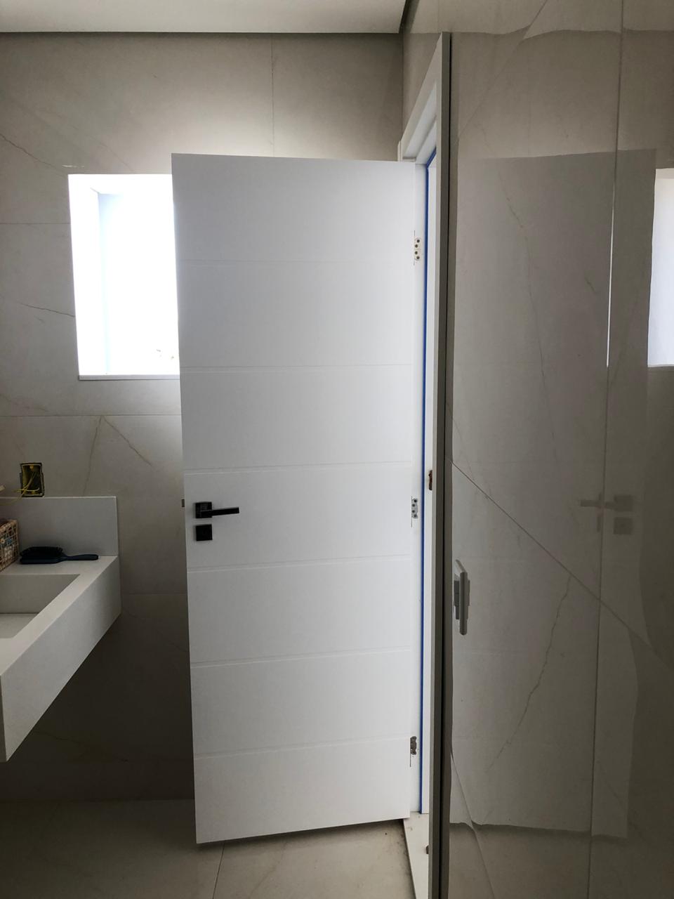 Um banheiro com uma pia e uma porta branca.