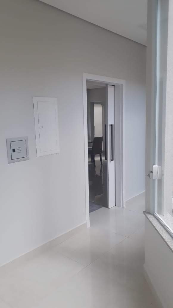 Um corredor com uma janela e uma porta que leva a uma sala.