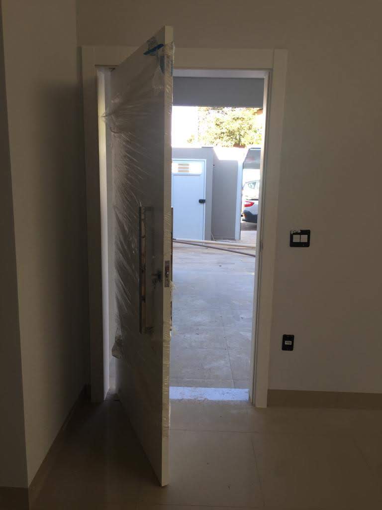 Uma porta está aberta em uma sala com vista para uma garagem.