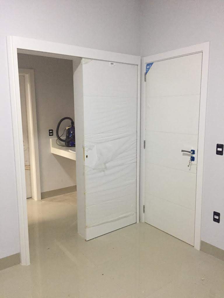 Um quarto com duas portas brancas que levam a um banheiro.