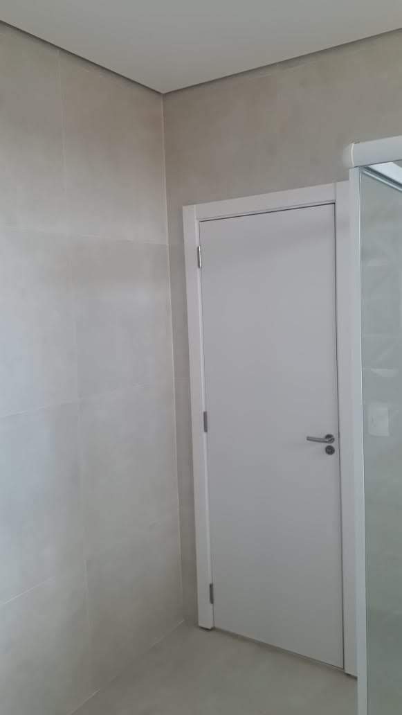 Um banheiro com uma porta branca e um box de vidro.