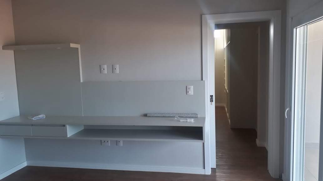 Uma sala vazia com uma televisão na parede e uma porta que levava a um banheiro.