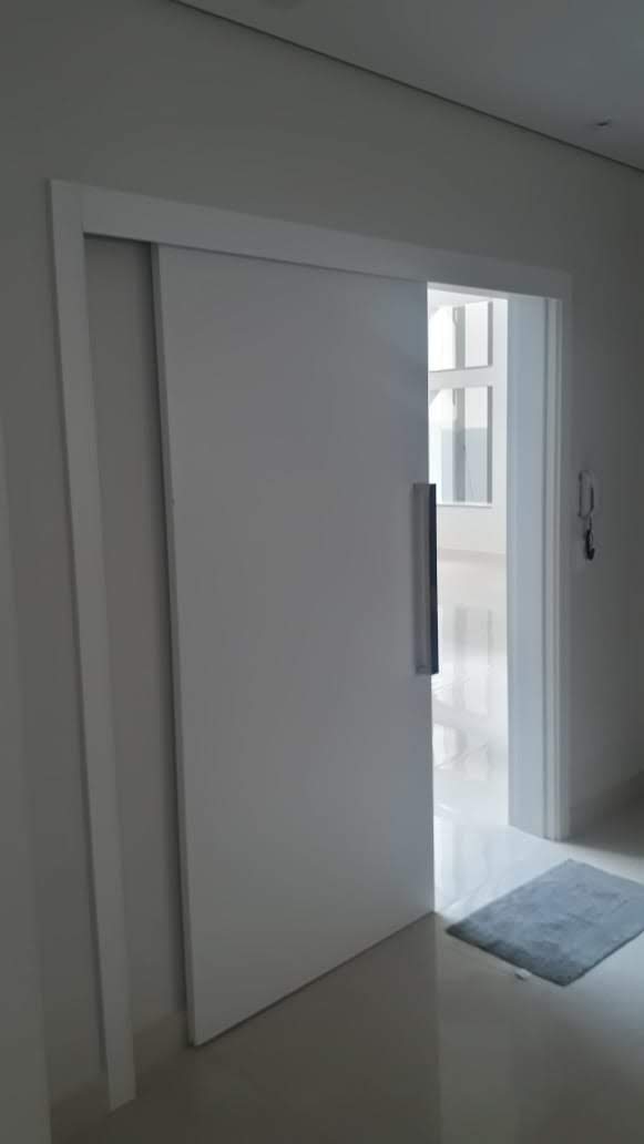 Uma porta de correr branca está aberta em um corredor.