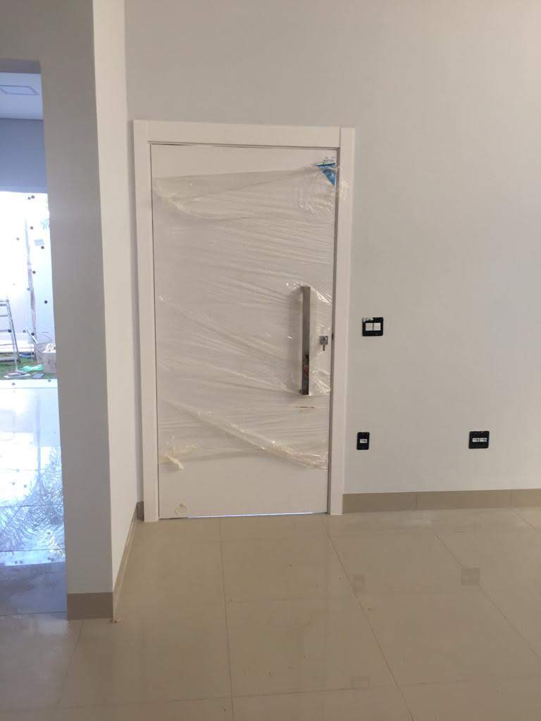 Uma porta branca está envolta em plástico em uma sala vazia.