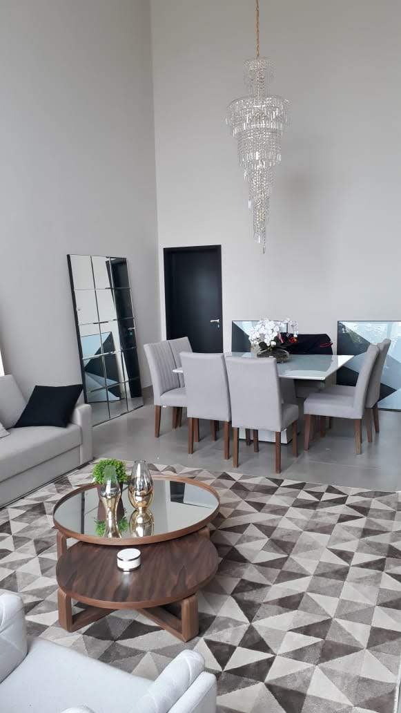 Uma sala de estar com um sofá, cadeiras, uma mesa e um tapete.