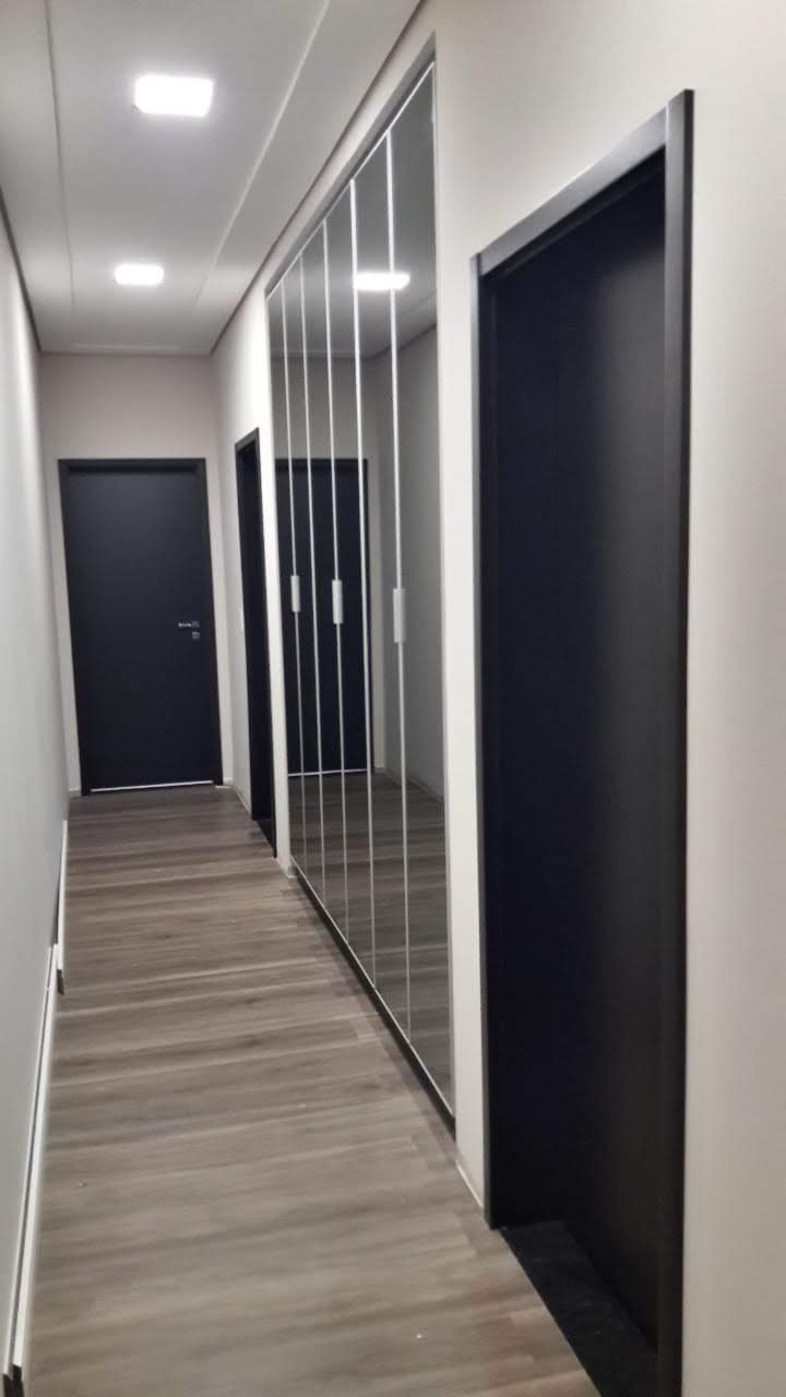Um longo corredor com portas pretas e espelhos na parede.