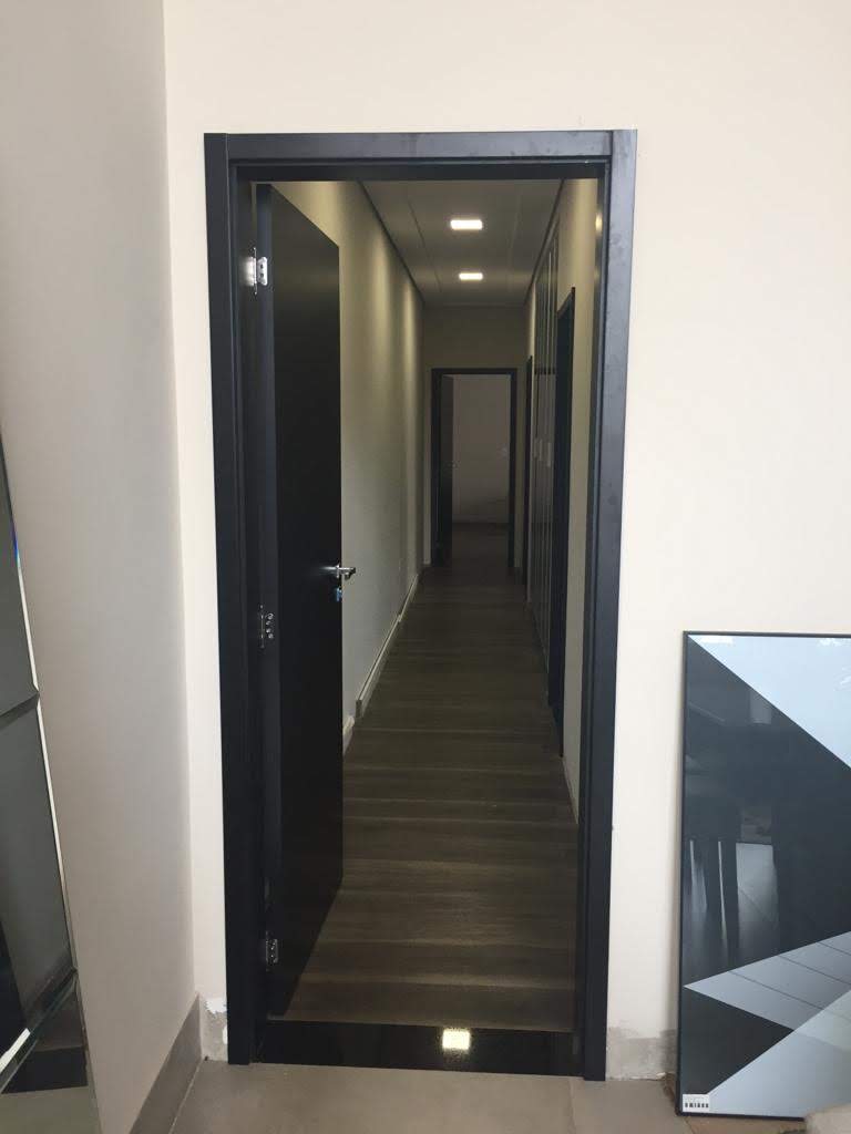 Um corredor com uma porta preta e uma foto na parede