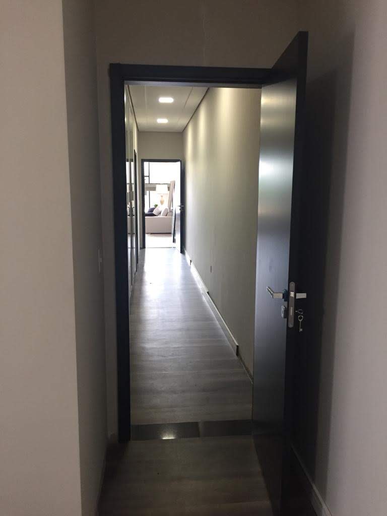 Um longo corredor com uma porta preta que levava a uma sala.