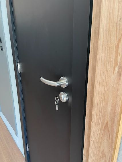 Uma porta preta com uma maçaneta prateada e uma chave.