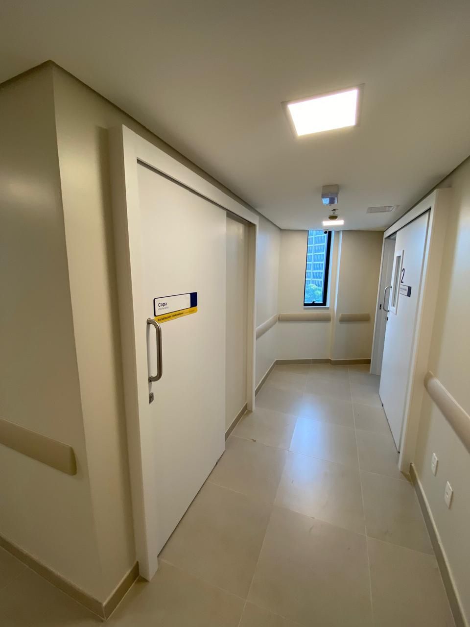 Um corredor de hospital com portas de correr e uma janela.