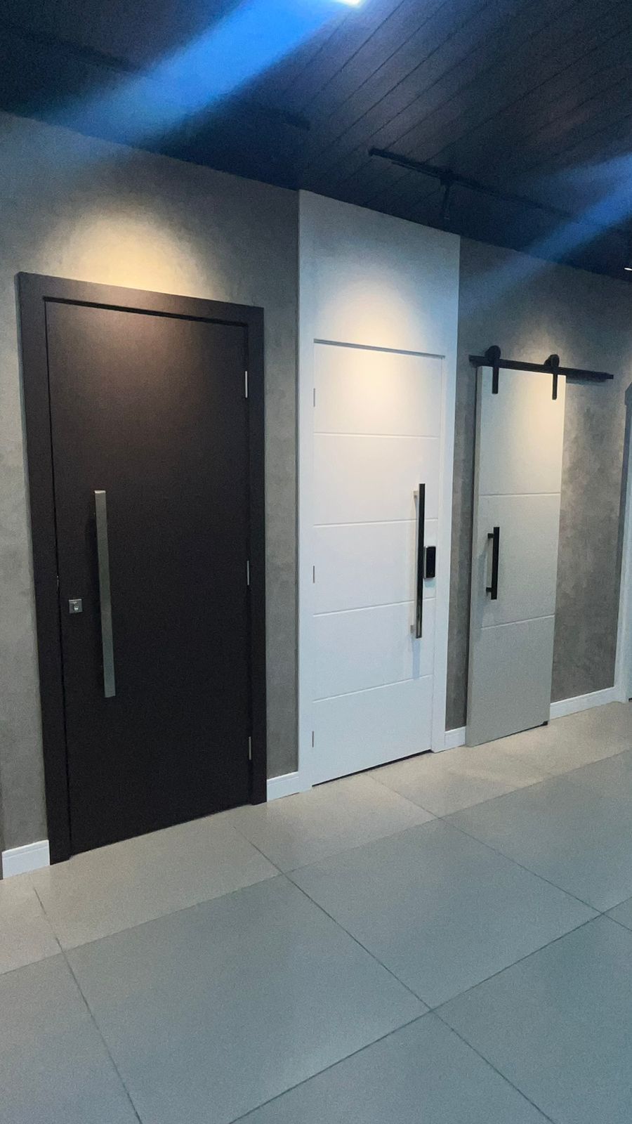 Uma fileira de portas estão alinhadas em um corredor.